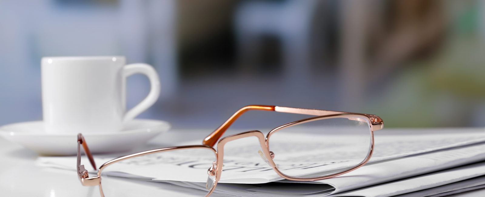 Newspaper, coffe mug and glasses on a table